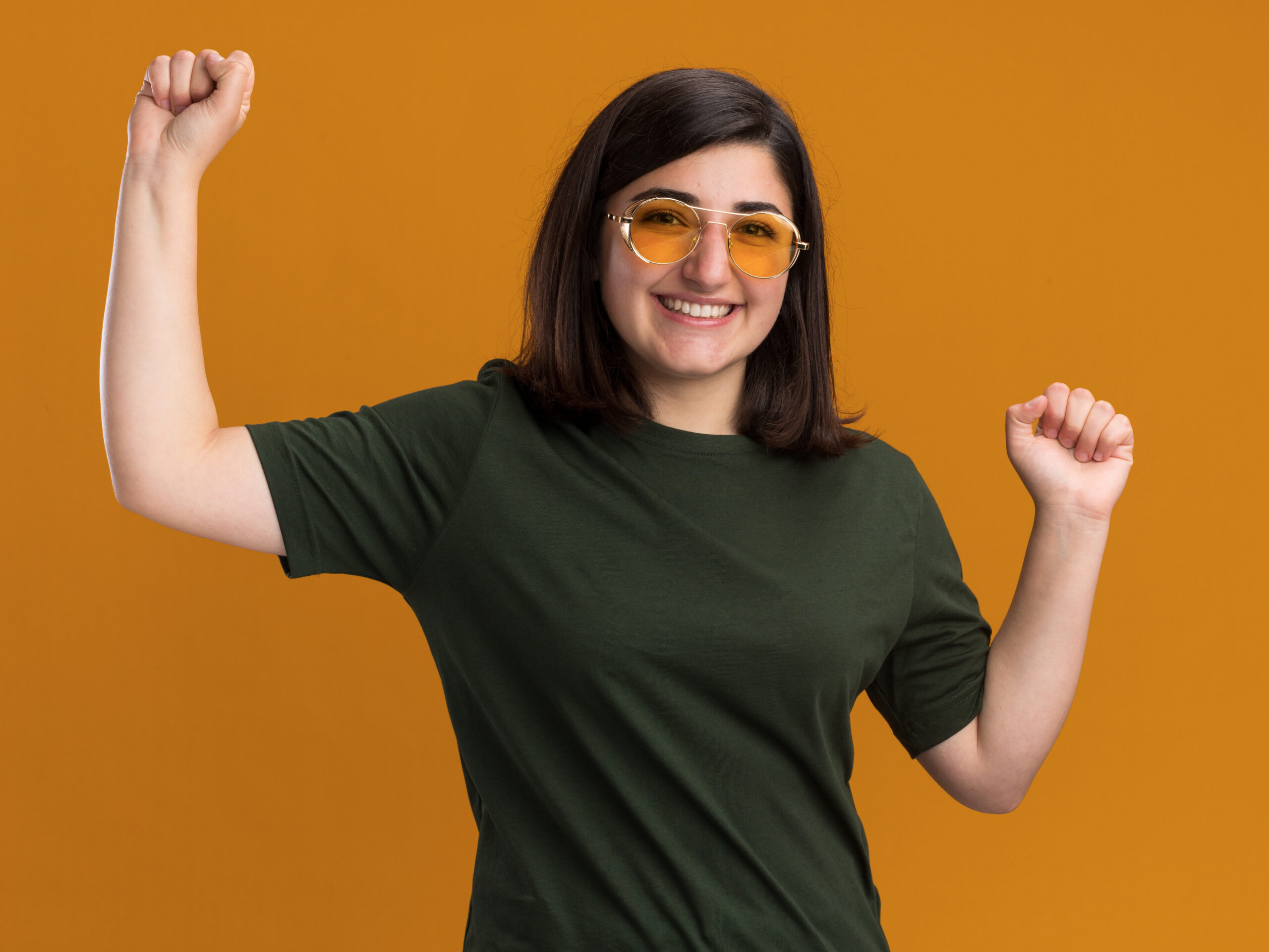 Home Smiling Young Pretty Caucasian Girl Sun Glasses Stands With Raised Fists Orange Scaled