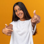 Home Young Girl White T Shirt Looking Camera Smiling Cheerfully Pointing With Index Figners Camera Standing Orange 150x150