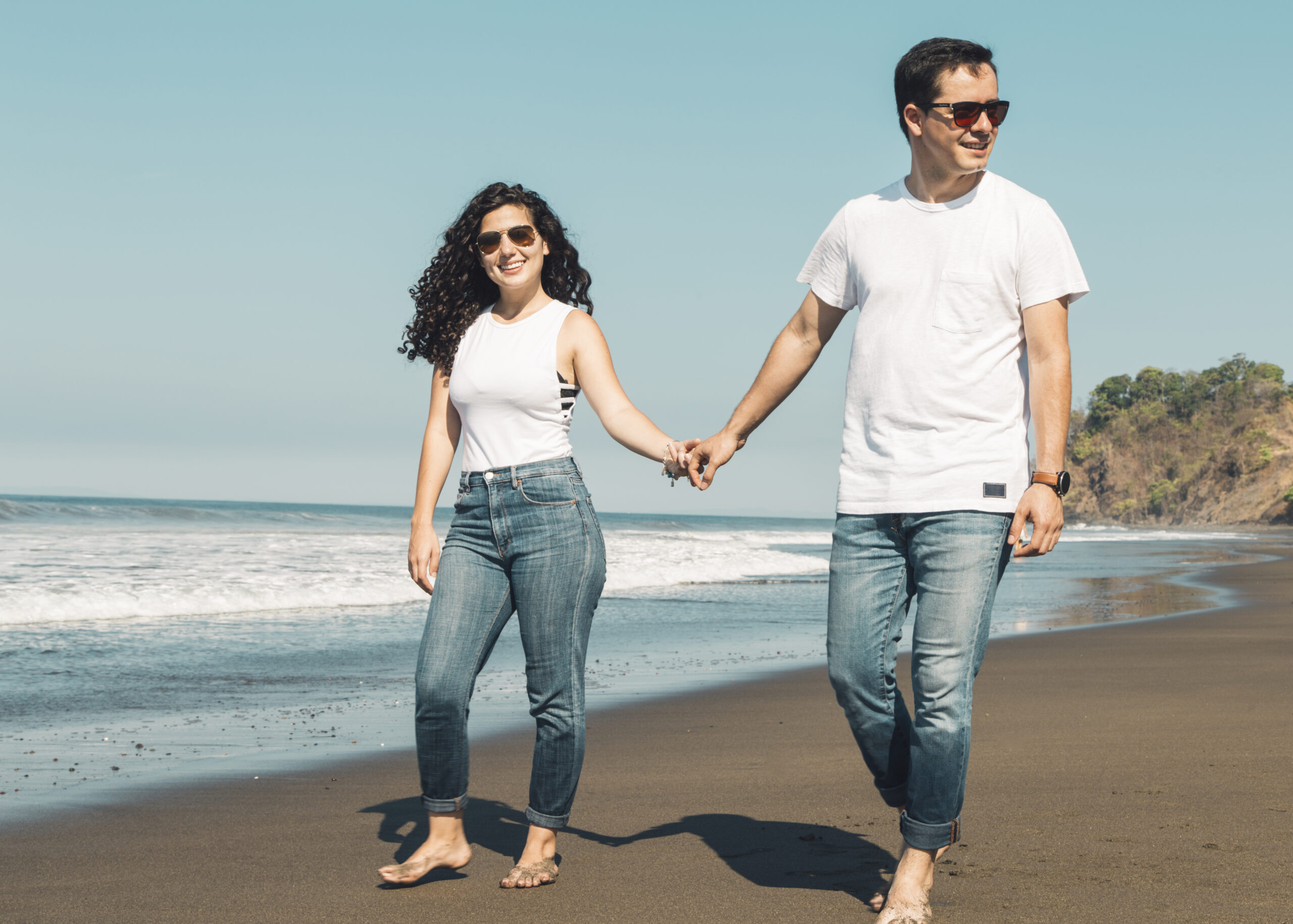 Home couple walking barefoot sandy beach